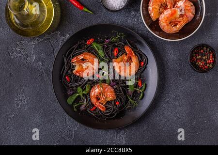 Italienische Pasta schwarze Spaghetti mit Garnelen und Microgreens, Draufsicht. Stockfoto