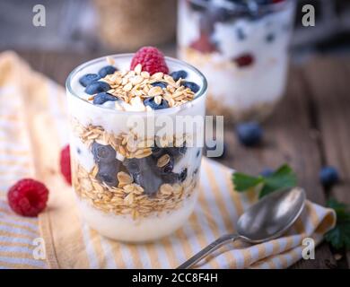 Weißer Joghurt im Glas mit Früchten auf gelber Serviette. Stockfoto