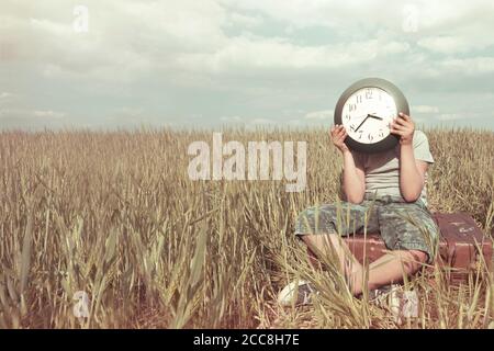 Junge auf einer Reise versteckt sein Gesicht mit einer Uhr In einer Wüstenlandschaft Stockfoto