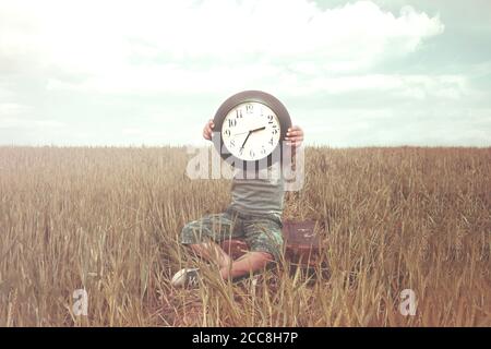 Junge auf einer Reise versteckt sein Gesicht mit einer Uhr In einer Wüstenlandschaft Stockfoto