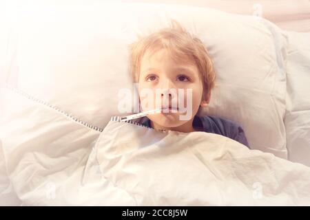 Kind krank im Bett mit Fieber und Thermometer Stockfoto