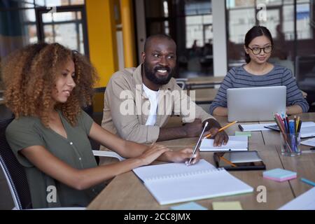 Austausch neuer Ideen. Ein junges multikulturelles Business Team arbeitet im modernen Coworking Space zusammen und diskutiert während eines Meetings über neue Projekte Stockfoto