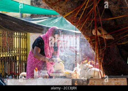 Orchha, Madhya Pradesh, Indien - März 2019: Portrait einer indischen Hindu-Anhängerin, die Rituale mit Räucherstäbchen an einem Schrein am Straßenrand durchführt Stockfoto