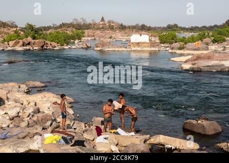 Orchha, Madhya Pradesh, Indien - März 2019: Menschen, die am felsigen Ufer des Betwa Flusses im Dorf Orchha baden. Stockfoto