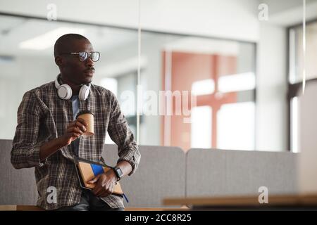 Afrikanischer junger Geschäftsmann in legerer Kleidung, der Kaffee trinkt, hat er Eine Kaffeepause Stockfoto