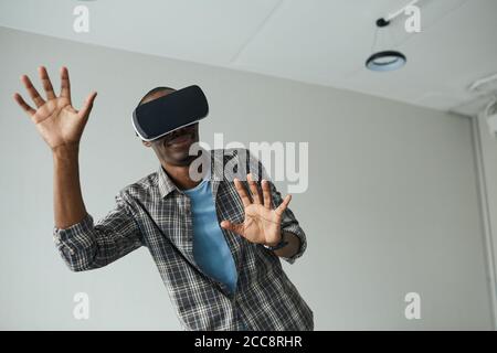 Afrikanischer junger Mann mit VR-Brille spielt er in virtuellen Reality-Spiel Stockfoto