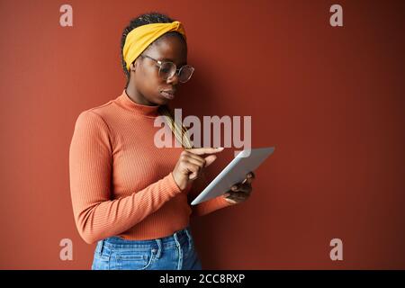 Afrikanische junge Frau in Brillen konzentriert sich auf ihre Online-Arbeit Sie verwendet ein digitales Tablet Stockfoto