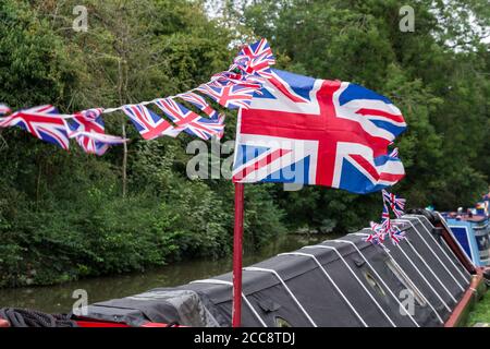 Union Jack Flagge und Ammer fliegen von einem Schmalboot, Stoke Bruerne, Northamptonshire, Großbritannien; dekoriert für das jährliche Dorf bei Kriegsereignis. Stockfoto