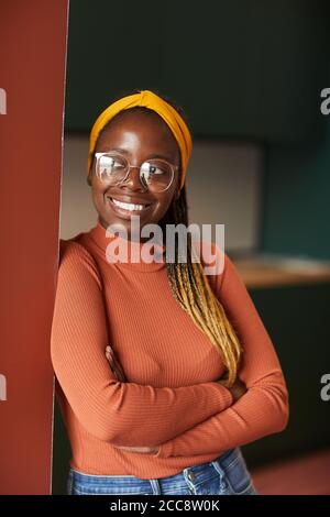 Afrikanische junge glückliche Frau in lässiger Kleidung und mit stilvollen Frisur lächelt an der Kamera Stockfoto
