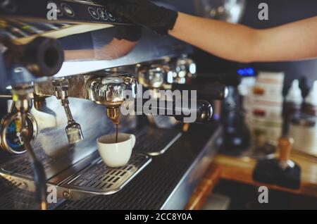Barista trägt medizinische Latex schwarze Handschuhe, Vorbereitung Kaffee trinken mit Espresso-Maschine in Café.verschwommenes Bild, selektiver Fokus Stockfoto