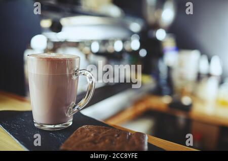 Rosa Matcha Latte mit Milch im Café. Leckeres Getränk und Brownie-Kuchen. Verschwommenes Bild, selektiver Fokus Stockfoto