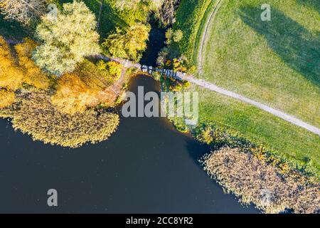Herbstlandschaft Seeufer mit bunten Bäumen und Fußweg im Sonnenlicht. Luftaufnahme von oben Stockfoto