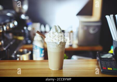 Frappe: Im Café wird ein vereistter Latte-Kaffee mit Karamell- und Schokoladensirup sowie Schlagsahne serviert. Kaffeepause. Verschwommenes Bild, selektiver Fokus Stockfoto