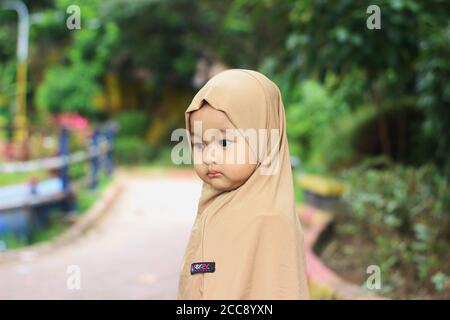 Ein nettes schönes moslemisches indonesisches Baby Mädchen im Park Stockfoto