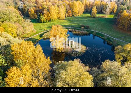 Schöne Landschaft des Herbstparks mit kleinem Teich umgeben von bunten gelben Bäumen. Luftbild Stockfoto