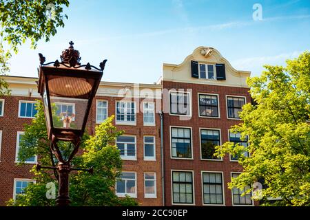 Fassade des alten Gebäudes und alte Straßenlaterne davor. Amsterdam - Juni 2019 Niederlande. Stockfoto