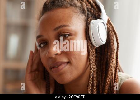 Nahaufnahme einer afrikanischen jungen Frau mit stilvoller Frisur in kabellosem Design Kopfhörer und Blick auf die Kamera Stockfoto