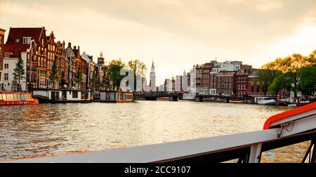 Kanal in Amsterdam mit Ausflugsboot und historischen Gebäuden. Blick vom Boot Stockfoto