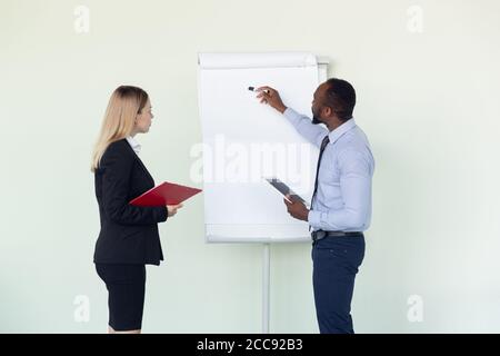 Junge Geschäftsmann und Frau warten auf die Abreise im Flughafen, Geschäftsreise, Business-Lifestyle. Mann und Frau arbeiten mit Flipchart in einer speziellen Konferenzzone, bevor sie ihren Urlaub beginnen, Anmeldung. Stockfoto