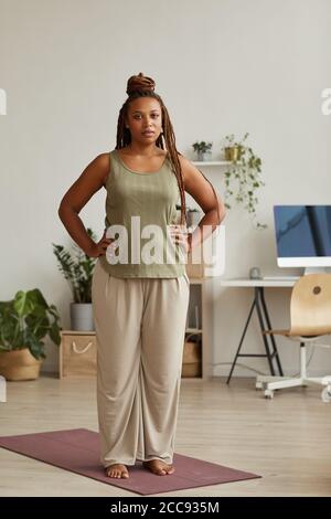 Porträt einer afrikanischen jungen Frau in Sportkleidung, auf der sie steht Übungsmatte und Blick auf die Kamera sie dabei Aerobic an Zu Hause Stockfoto