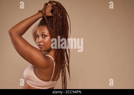 Portrait von afrikanischen Mode-Modell mit schönen Frisur posiert bei Kamera auf braunem Hintergrund isoliert Stockfoto
