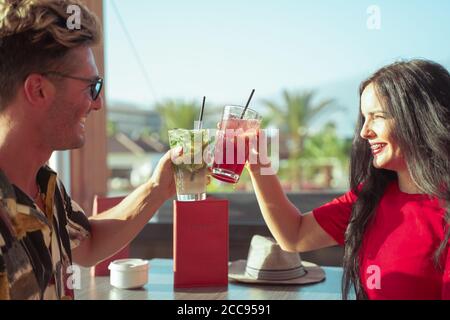 Ein glückliches Paar trinkt Cocktails bei einer Party im Freien. Junge Millennials Menschen Spaß am Wochenende Sommertag. Jugend Lifestyle und Liebe Konzept. Stockfoto