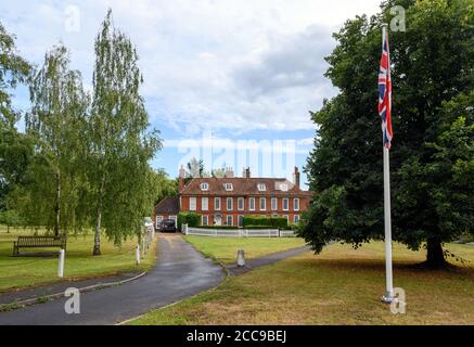 Ein großes altes Haus in Otford, Kent, Großbritannien in der Nähe des Dorfteiches. Im Vordergrund ist eine Wiese mit Bäumen und der britischen Gewerkschaftsflagge. Stockfoto