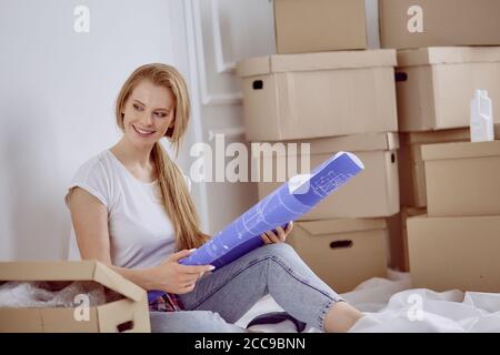 Mädchen sitzt zwischen Boxen macht Marken auf dem Plan der Wohnung Stockfoto