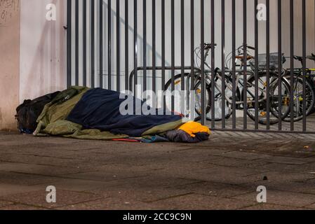 Obdachloser im Winter schlafend, Obdachloser im Schlafsack auf der Straße, Bürgersteig Stockfoto