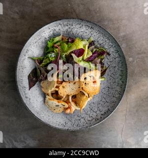 Caesar Salat mit Garnelen auf schwarzem Teller Stockfoto