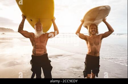 Mehrgenerationige Freunde, die am tropischen Strand surfen - Familienmitglieder haben Spaß am Extremsport - fröhliches älteres und gesundes Lifestyle-Konzept Stockfoto