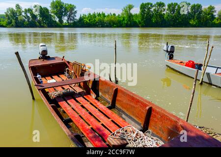 Rotes Fischerboot aus Holz auf improvisiertem Dock auf dem Fluss verankert. Stockfoto