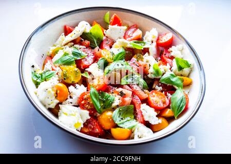 Hausgemachter Caprese Salat ein traditioneller italienischer Salat aus Capri aus frischen Tomaten, Büffelmozzarella mit Basilikumblättern und nativem Olivenöl Stockfoto