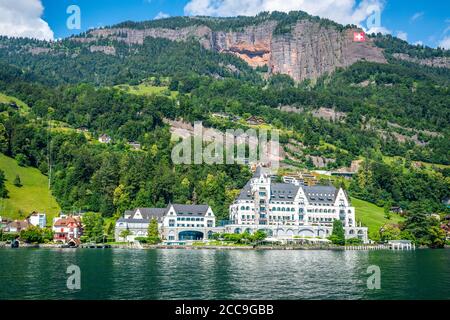 Vitznau Schweiz , 28. Juni 2020 : Luxury Park Hotel Vitznau vom Luzerner See und riesiger Schweizer Flagge an den Bergen in der Schweiz Stockfoto