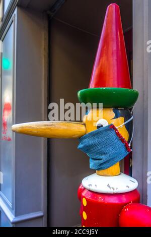 Pinocchio Figur mit Covid-19 Schutzmaske vor dem 'Jeu Jouet' Spielzeugladen in Angers, Maine-et-Loire, Frankreich. Stockfoto