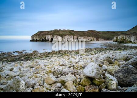 Malerische Bucht, felsiger Strand, hohe zerklüftete Kreidefelsen, ruhiges Meer, blauer Sommernachthimmel - Thornwick Bay, Flamborough, East Yorkshire Coast, England, Großbritannien. Stockfoto