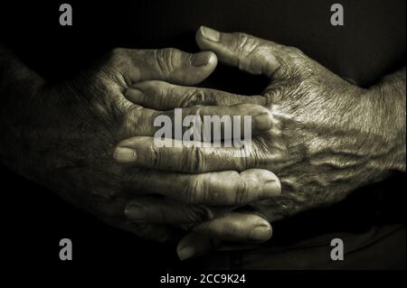 Ältere ältere ältere Erwachsene mit gekreuzten faltigen Händen in einer Ruhephase Und entspannende Position - schwarzer Hintergrund Stockfoto