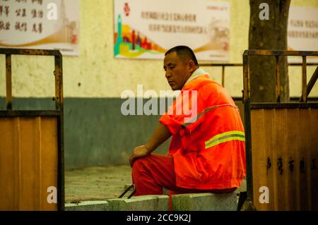 Eine Wanderarbeiterin macht eine Pause vom Wiederaufbau eines Straßenbelags im Zentrum von Shanghai auf Danshui Lu. Stockfoto