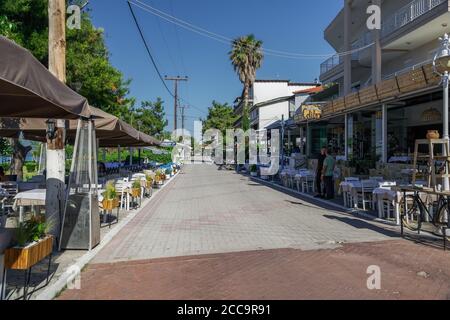 Chalkidiki, Griechenland Leere Tavernentische nach neuen covid-19 Maßnahmen. Restaurantpersonal neben dem Sitzbereich im Freien ohne Touristen in Hanioti. Stockfoto