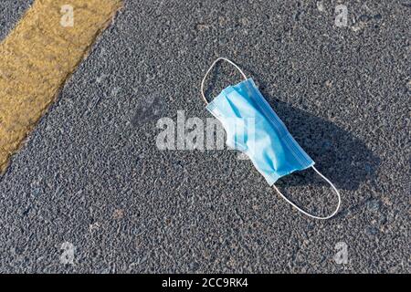 Gebrauchte medizinische Einweg-Gesichtsmaske auf der Straße entsorgt. Verschmutzung und Abfall während der Pandemie von Covid-19. Stockfoto