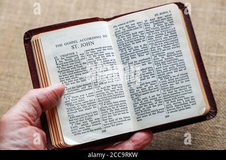 Eine rote Gideon-Bibel auf neutralem Hintergrund öffnete sich am Johannesevangelium. Das Buch enthält das Neue Testament und die Psalmen plus die Gebote Stockfoto