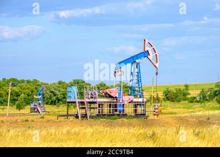 Schaukelstuhl für die Ölförderung in der trockenen Steppe an einem sonnigen Tag gegen den blauen Himmel. Industrieölförderung. Hochwertige Fotos Stockfoto