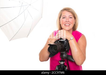 Horizontales Porträt eines Fotografen, der auf einer DSLR-Kamera auf einem Stativ in einem Studio arbeitet. Stockfoto