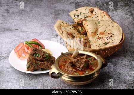 Hammelcurry serviert mit Naan oder Brot und Jeera-Reis auf Holzhintergrund. Stockfoto