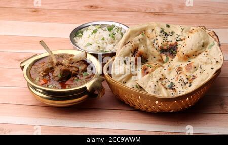 Hammelcurry serviert mit Naan oder Brot und Jeera-Reis auf Holzhintergrund. Stockfoto