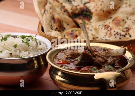 Hammelcurry serviert mit Naan oder Brot und Jeera-Reis auf Holzhintergrund. Stockfoto