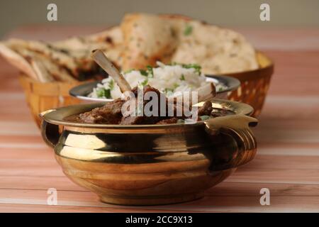 Hammelcurry serviert mit Naan oder Brot und Jeera-Reis auf Holzhintergrund. Stockfoto