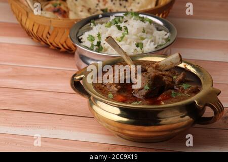 Hammelcurry serviert mit Naan oder Brot und Jeera-Reis auf Holzhintergrund. Stockfoto