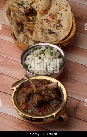 Hammelcurry serviert mit Naan oder Brot und Jeera-Reis auf Holzhintergrund. Stockfoto