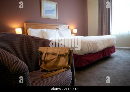 Ein Foto einer Handtasche auf einem Stuhl in einem Hotelzimmer. Stockfoto